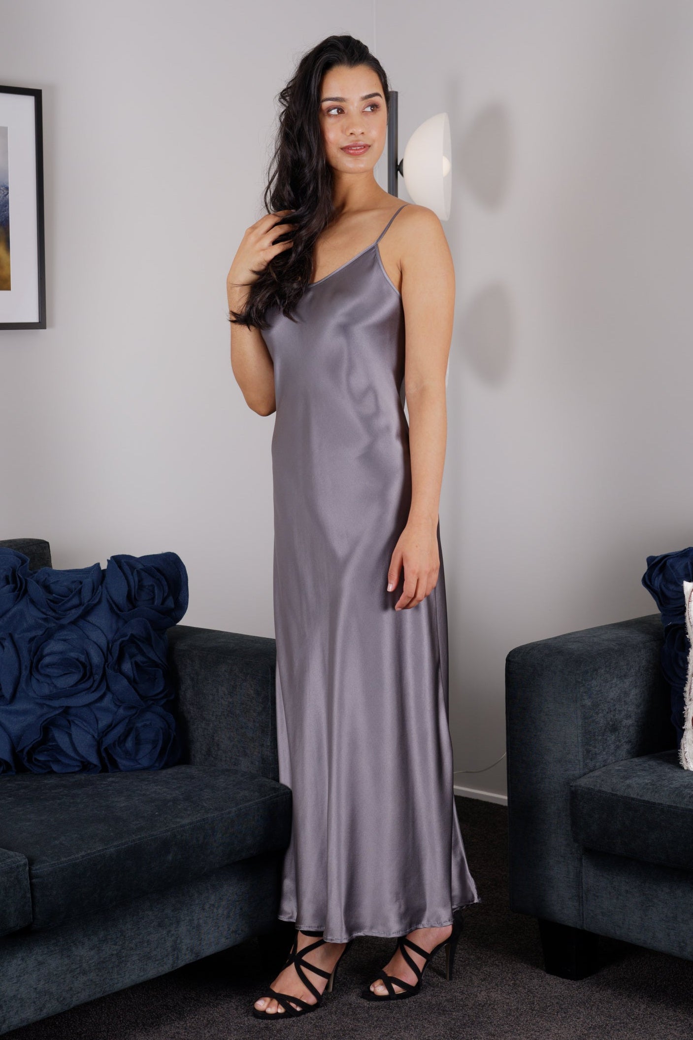women wearing a dark grey long silk chemise dress with v neck and adjustable straps