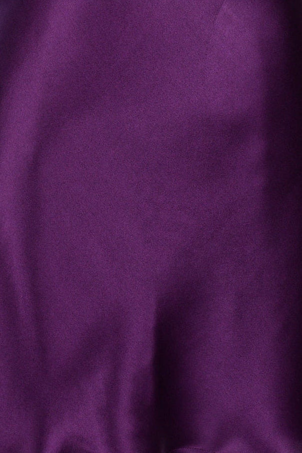 A close-up of draped purple fabric with soft folds and a smooth texture.