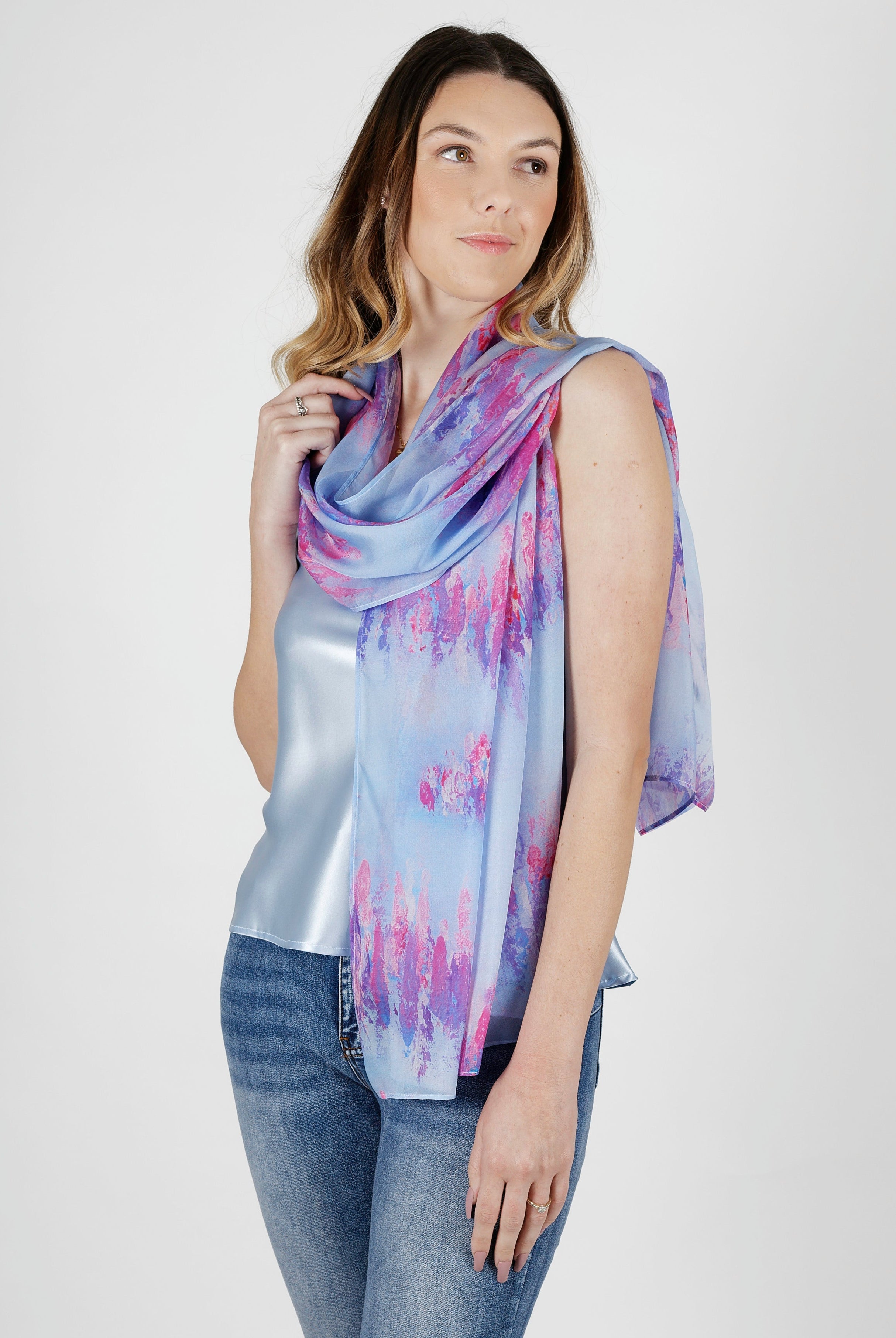 Woman wearing a blue and pink silk chiffon scarf and jeans on a white background