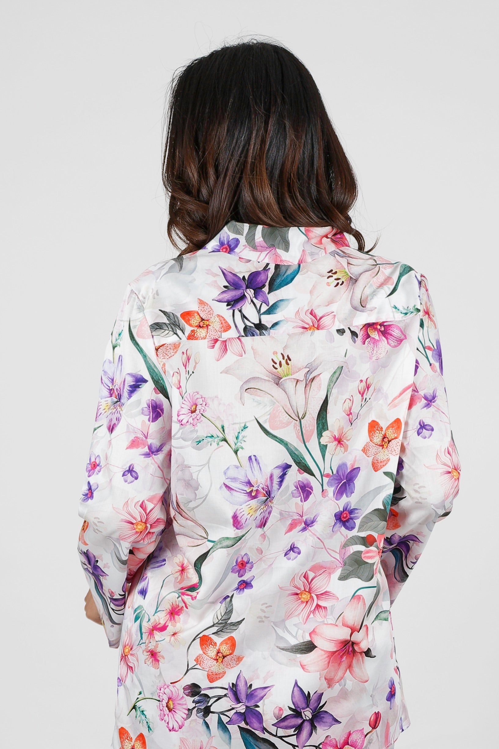 Person wearing a floral patterned shirt on a plain background