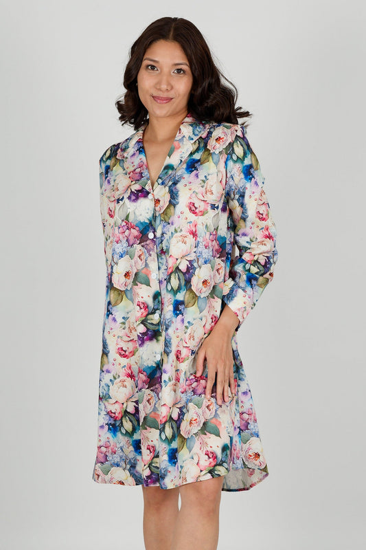 A model wearing a floral print cotton shirtdress nightie with a button-down front, collar, and full-length sleeves.