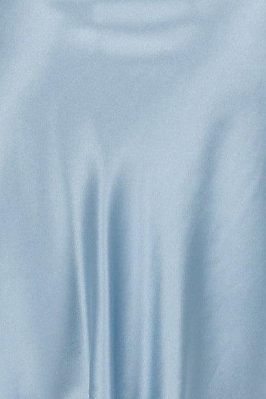 Woman wearing a light blue silk satin slip dress on a white background