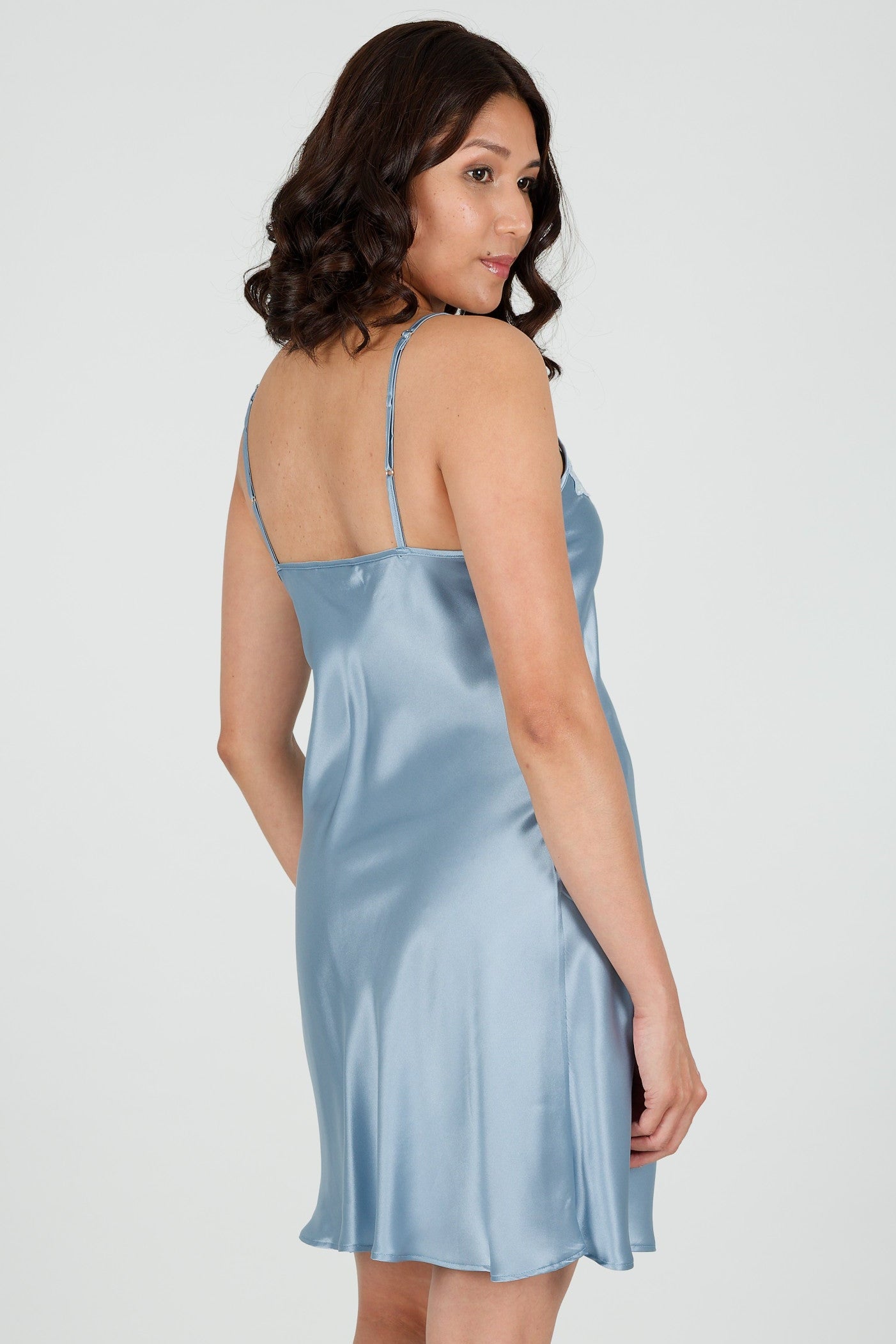Woman wearing a light blue silk satin nightgown on a white background