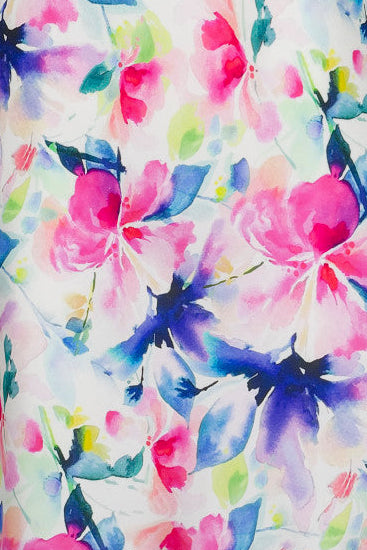 A woman wearing a floral silk chemise slip with vibrant hues of fuchsia pink, soft blue, and fresh green.