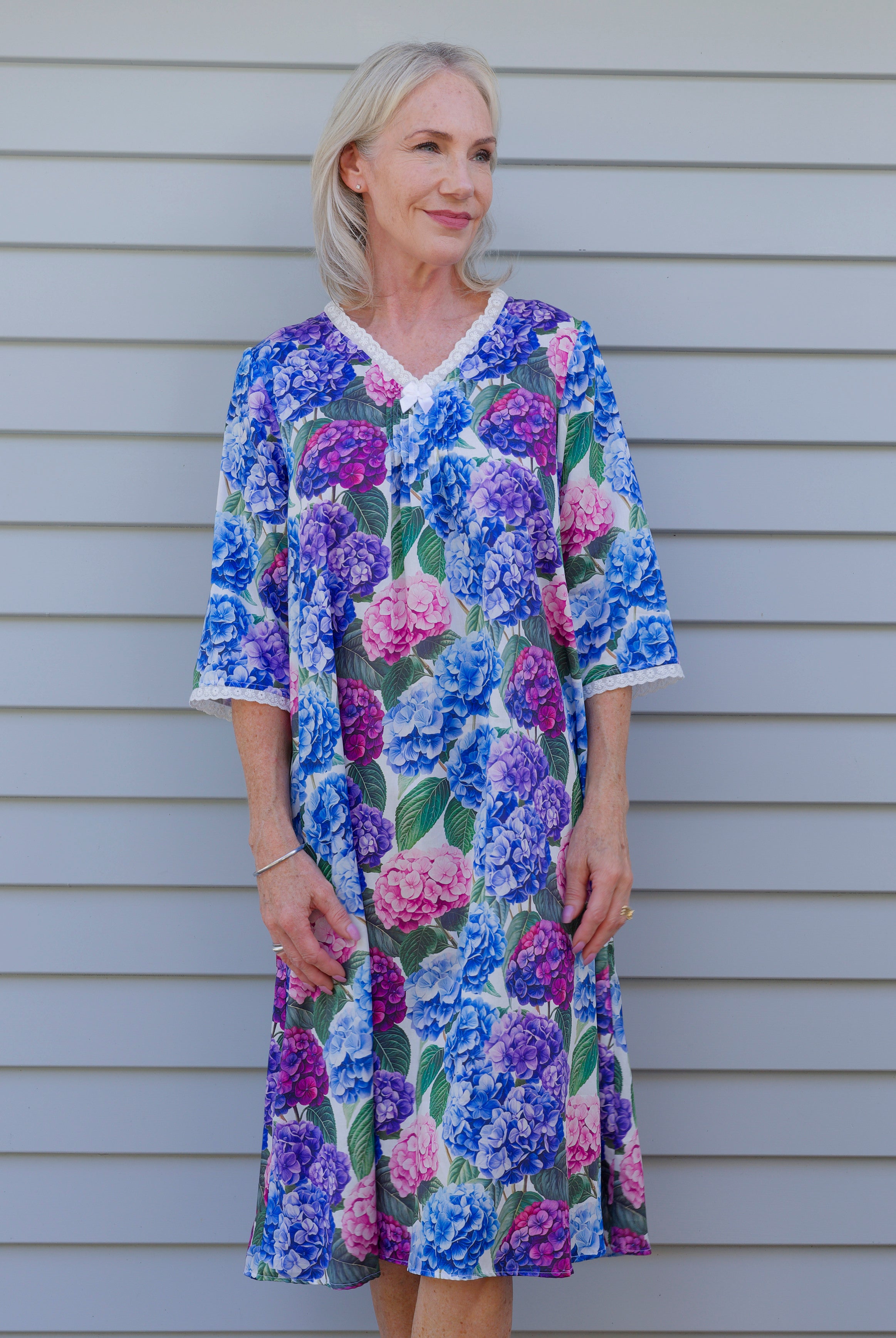 Woman wearing a floral cotton nightie with hydrangea flowers on it in blue purple and pink
