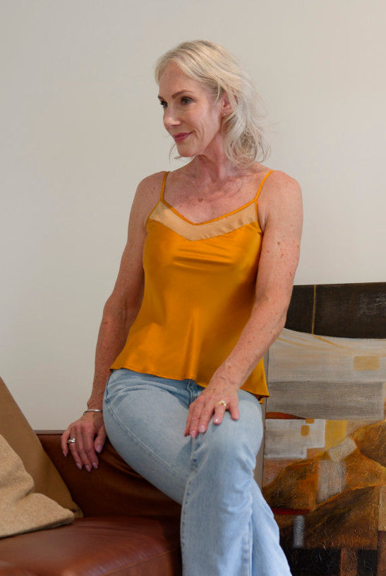 Woman in a bronze silk camisole top sitting on a brown couch