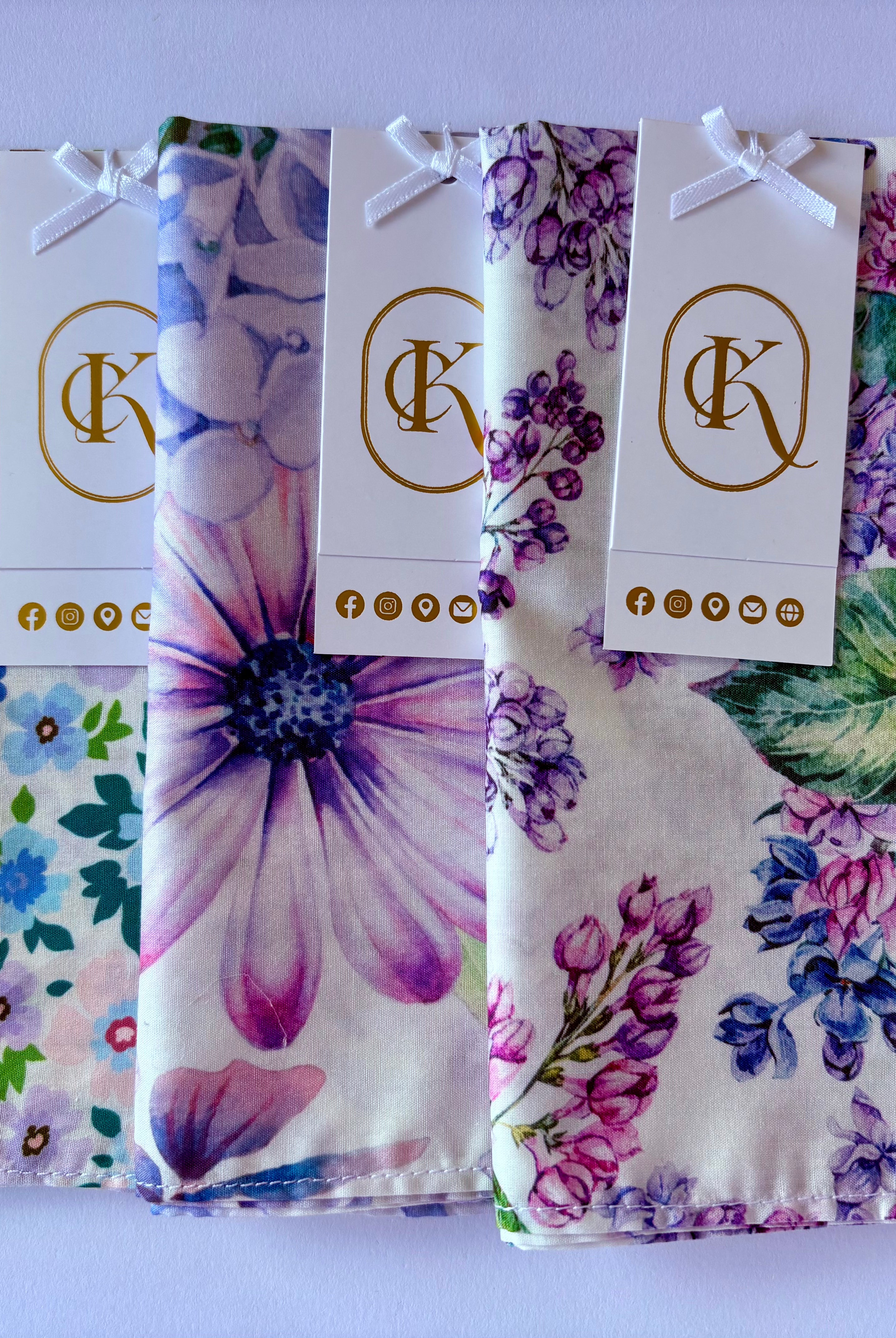 Three floral fabric womens hankies with matching tags on a white background