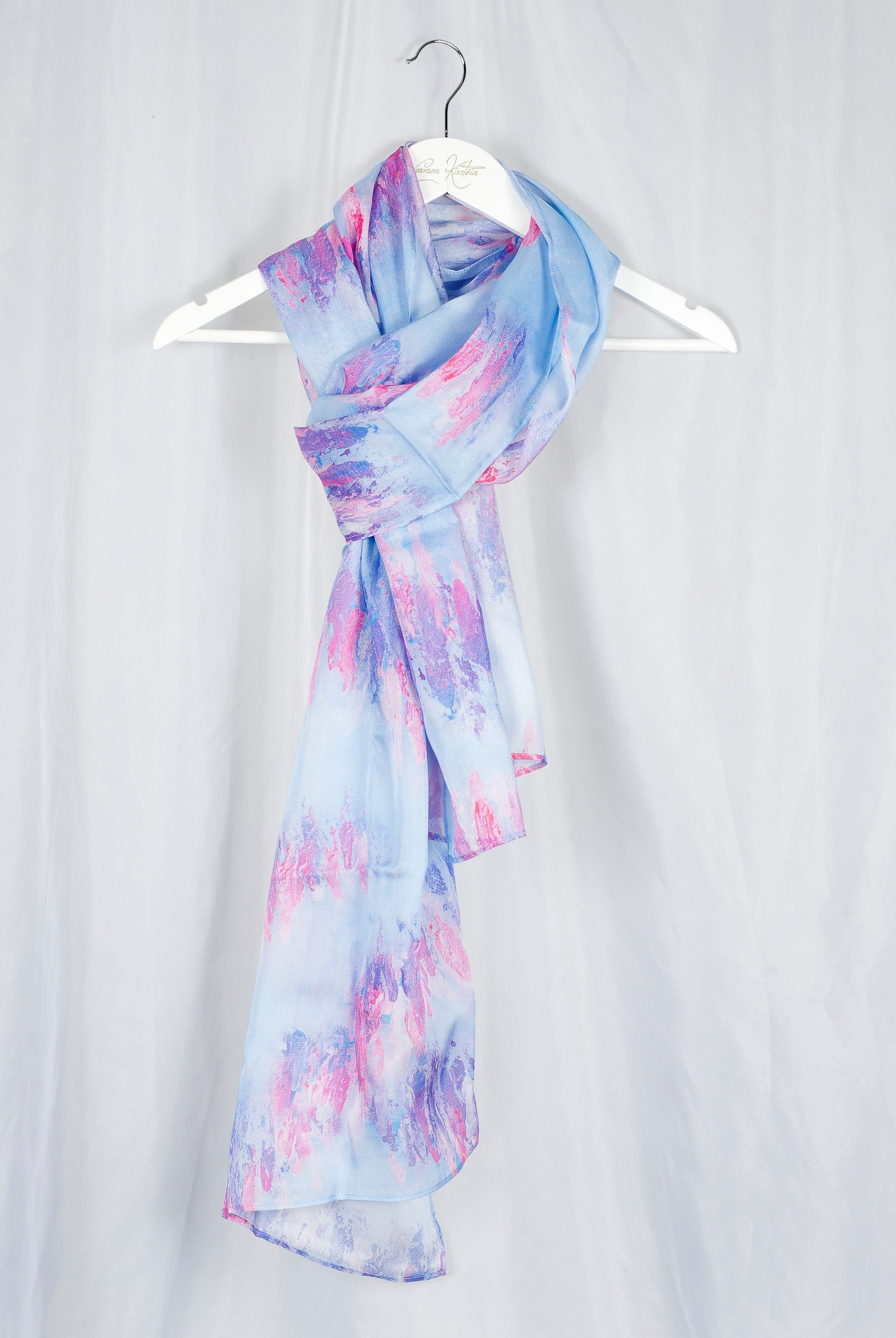 Light blue and pink silk chiffon scarf on a white hanger against a light gray background