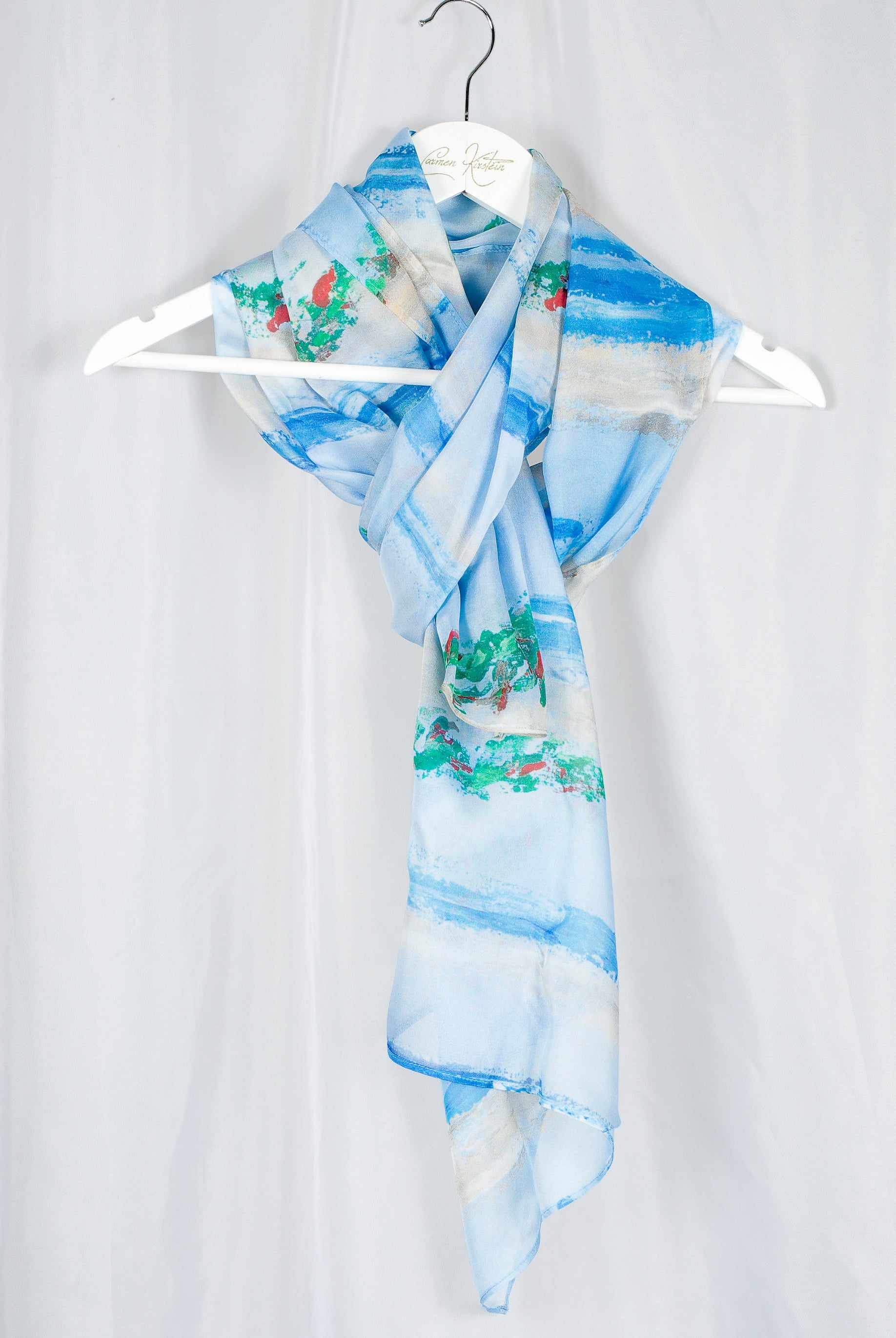 silk chiffon scarf in light blue and green and red print on hanger