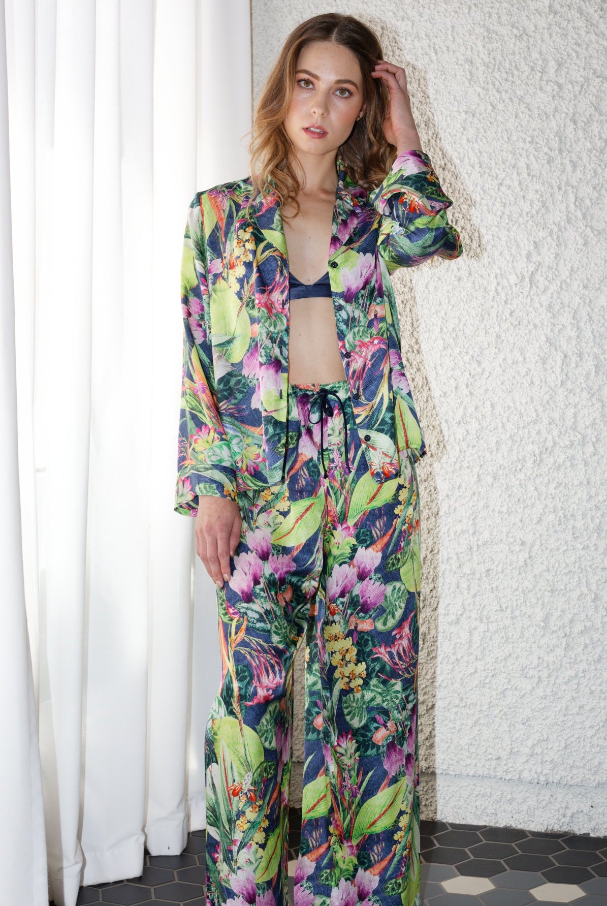 women wearing a bright green tropical print long sleeve silk shirt and matching pants