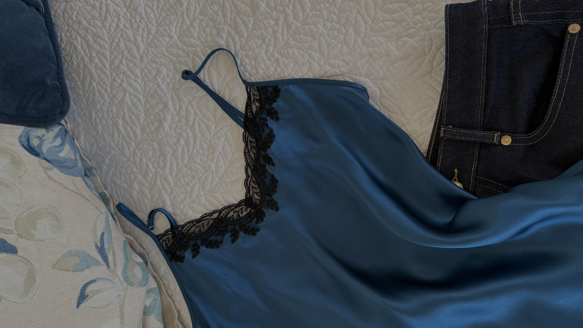 blue silk lace camisole draped on a bed