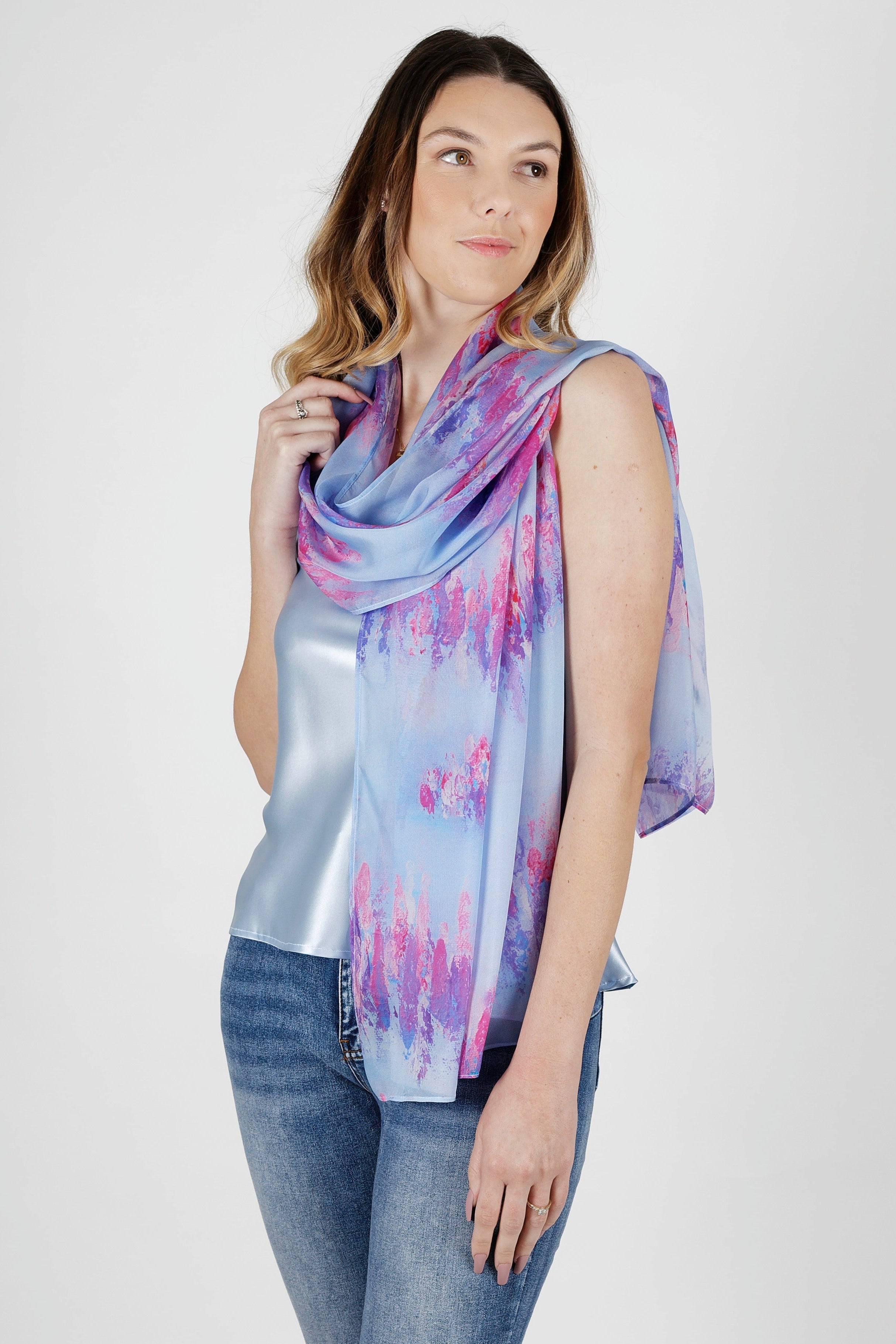 Woman wearing a blue and pink silk chiffon scarf and jeans on a white background
