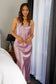 Woman wearing a purple silk satin slip dress in a bedroom setting.