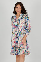 A model wearing a floral print cotton shirtdress nightie with a button-down front, collar, and full-length sleeves.