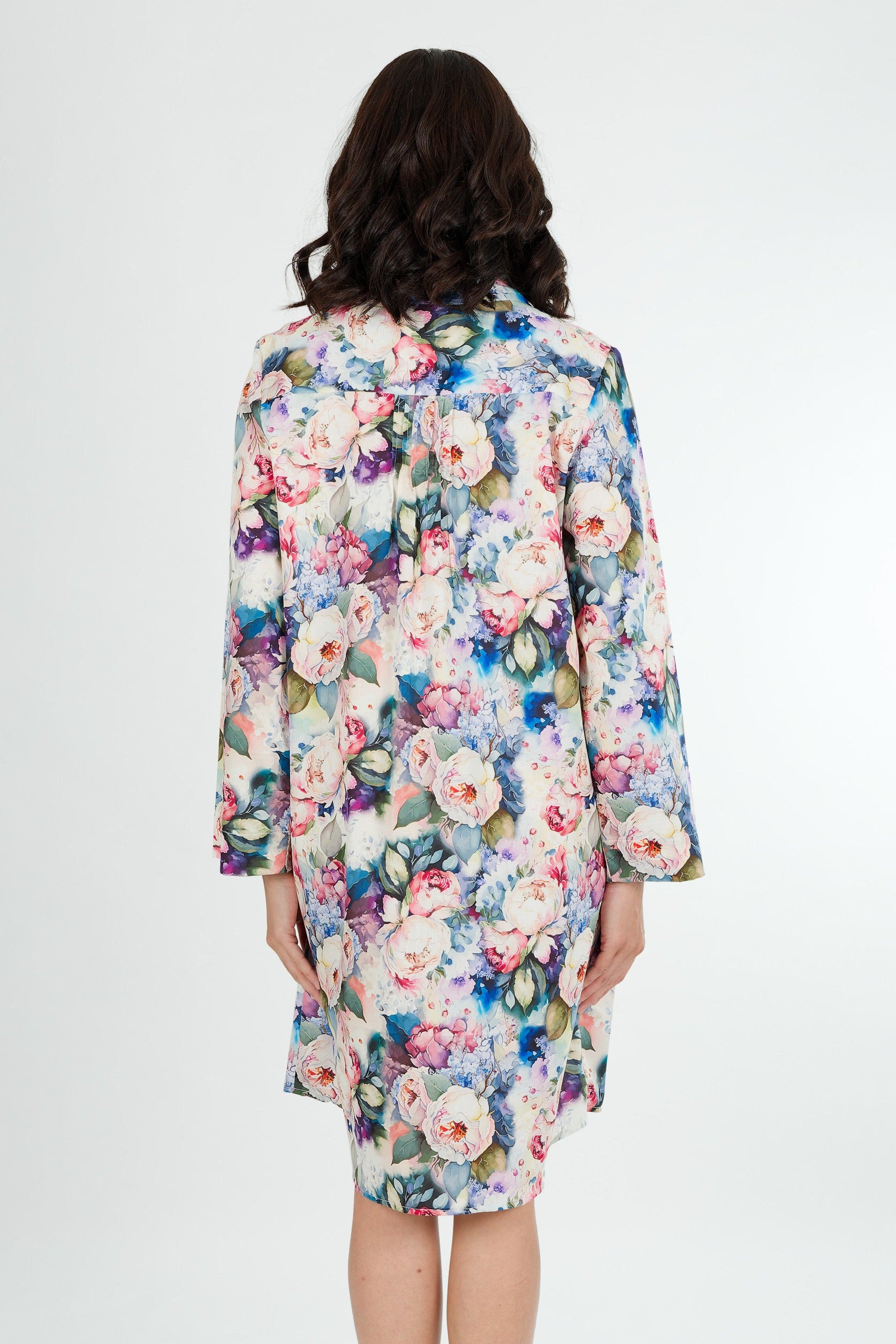A model wearing a floral print cotton shirtdress nightie with a button-down front, collar, and full-length sleeves.