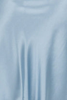 Woman wearing a light blue silk satin slip dress on a white background