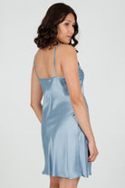 Woman wearing a light blue silk satin nightgown on a white background