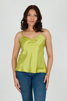 Woman wearing a green satin silk camisole and blue jeans 
