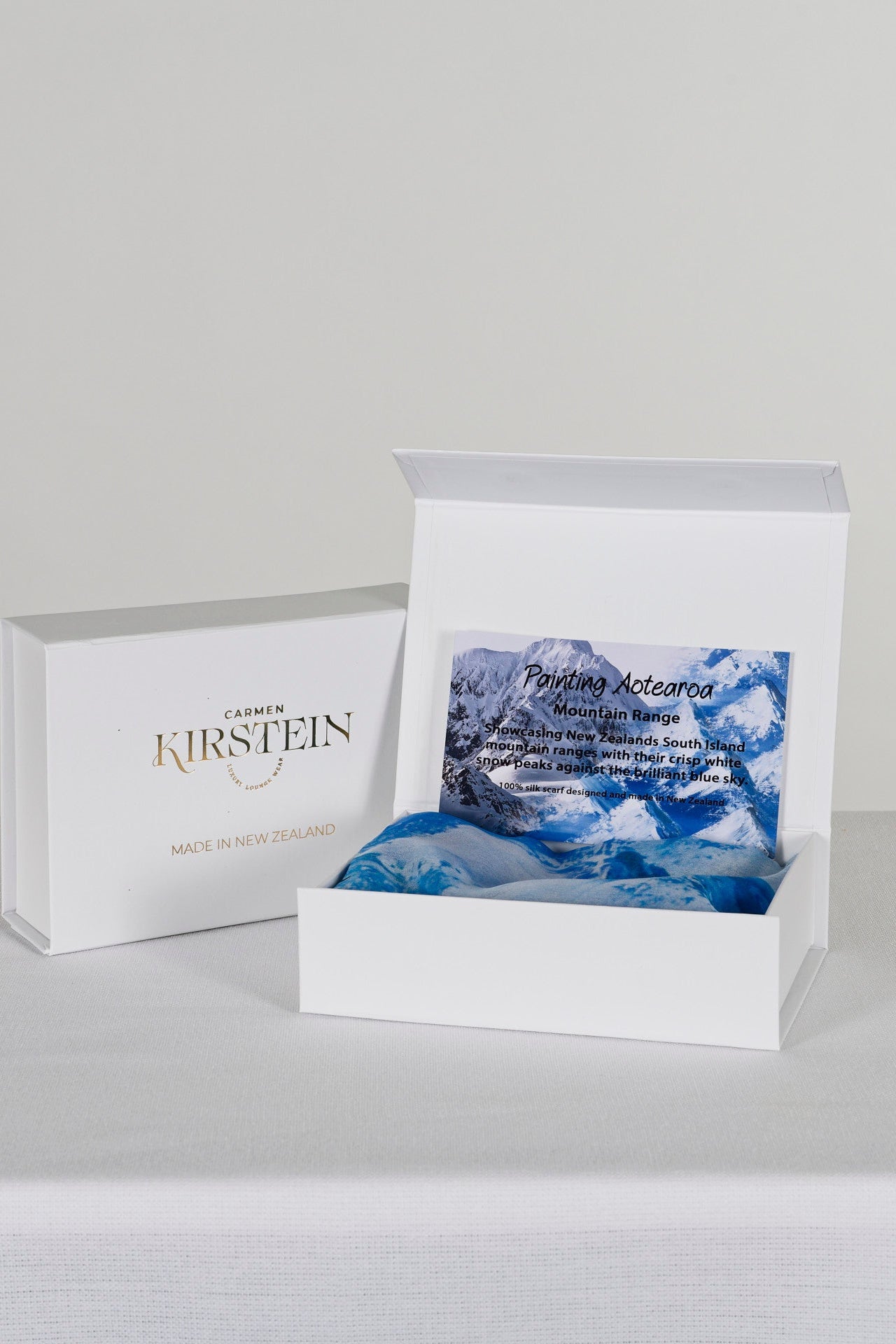 blue silk satin scarf with mountain print in a white box  