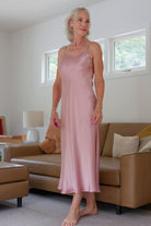 Woman in a pink silk satin slip dress nightie standing in a living room 