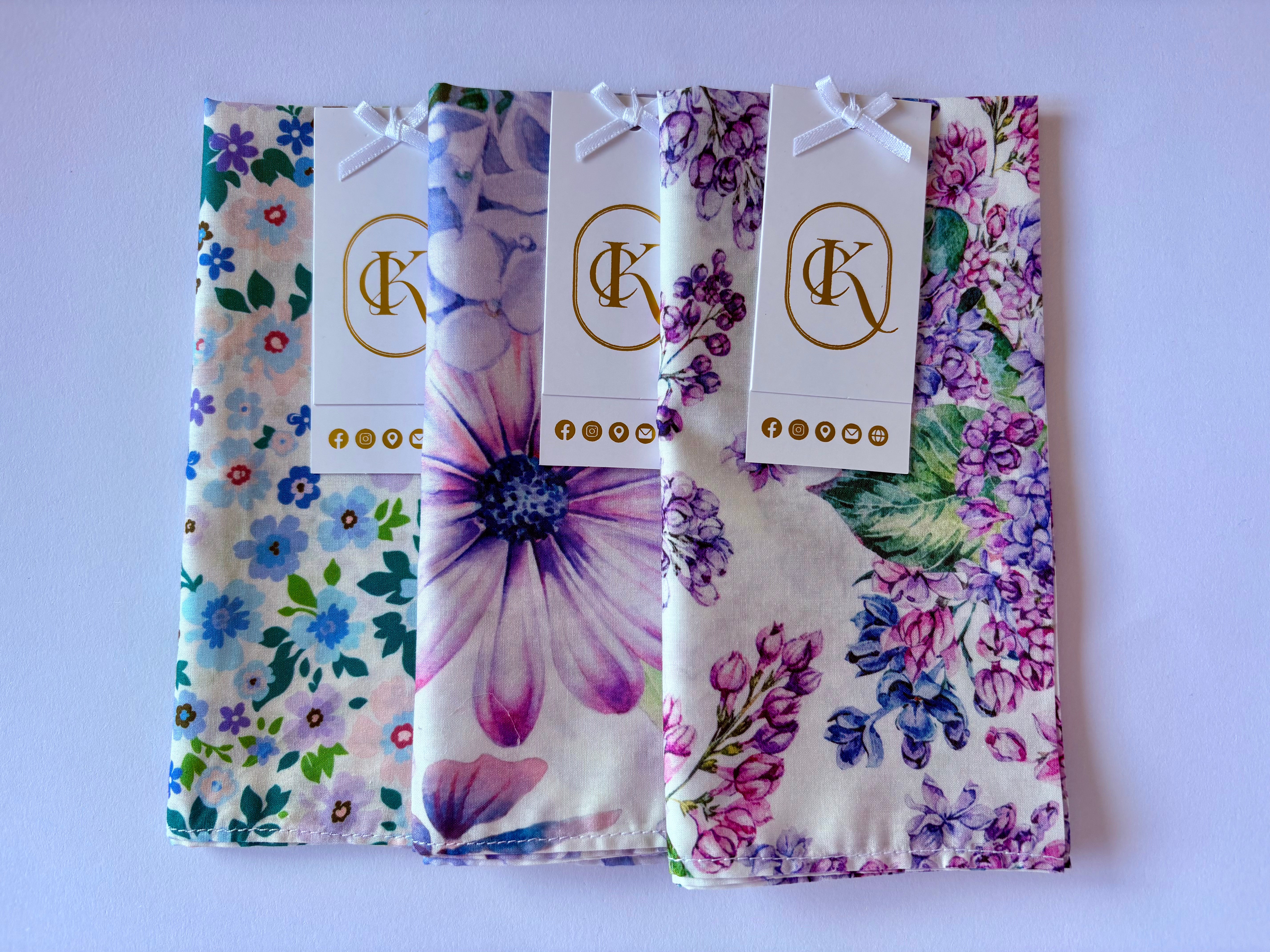 Three floral fabric womens hankies with matching tags on a white background