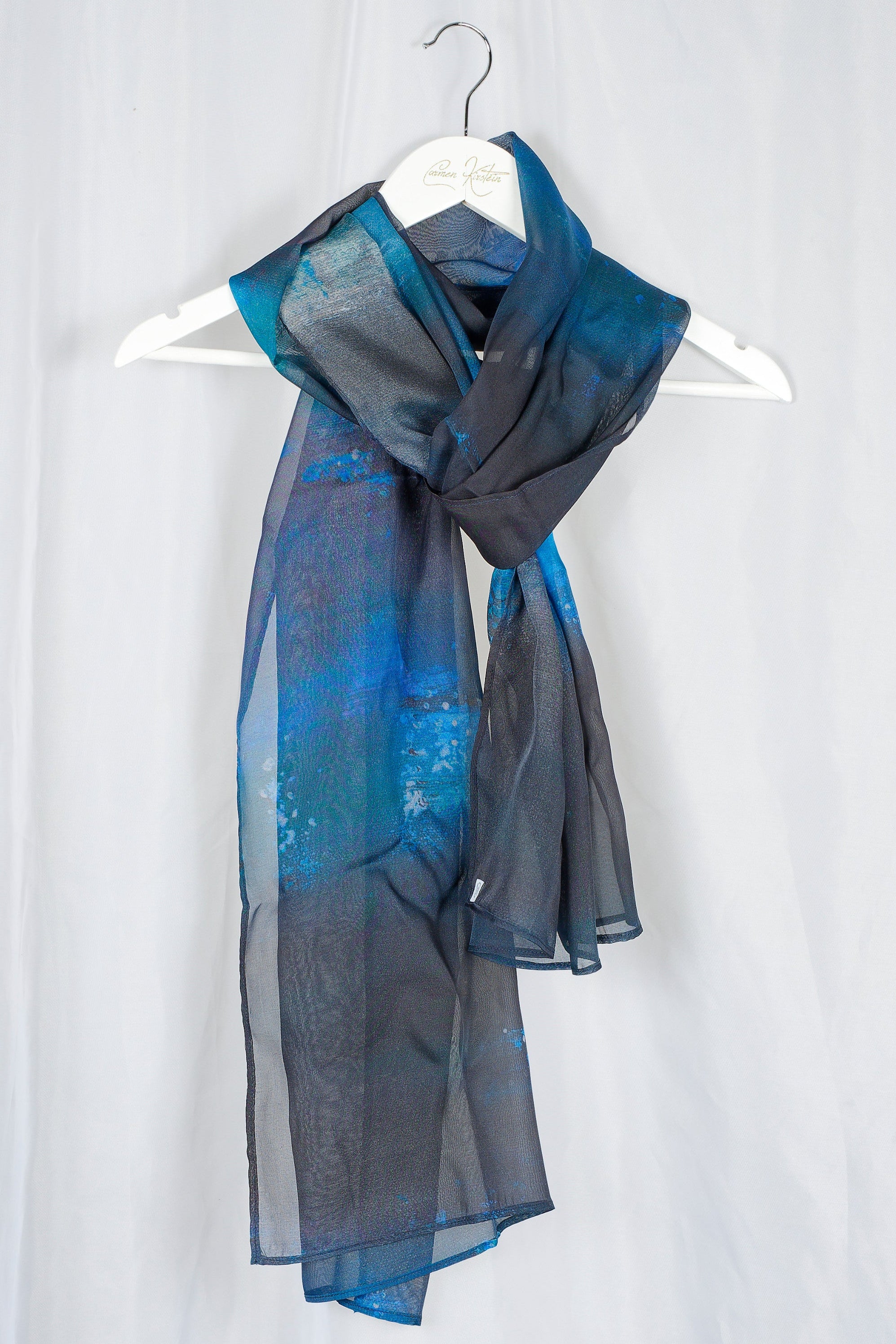 Blue and black silk chiffon scarf on a white hanger against a white background