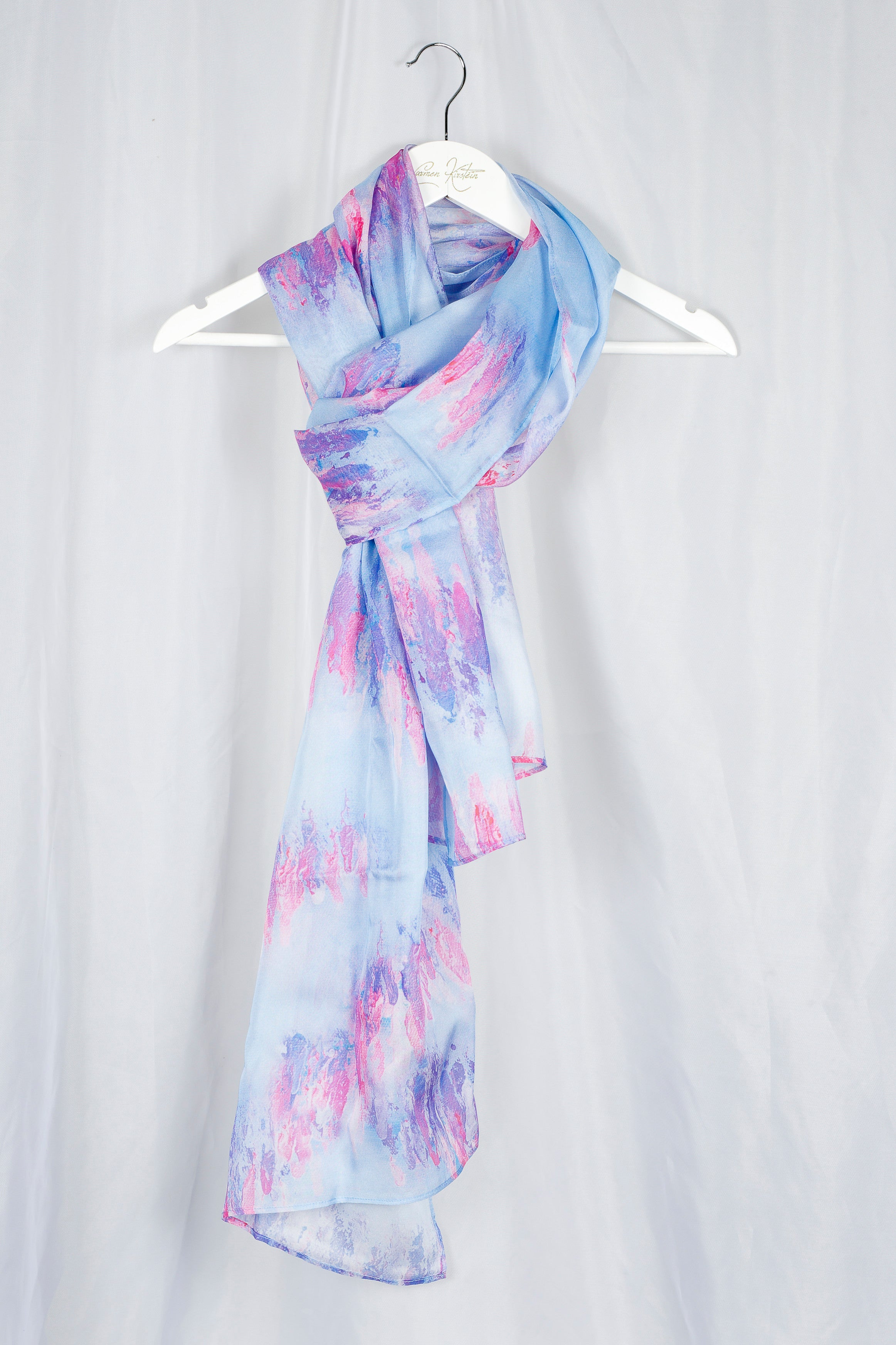 Light blue and pink silk chiffon scarf on a white hanger against a light gray background