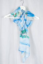 silk chiffon scarf in light blue and green and red print on hanger