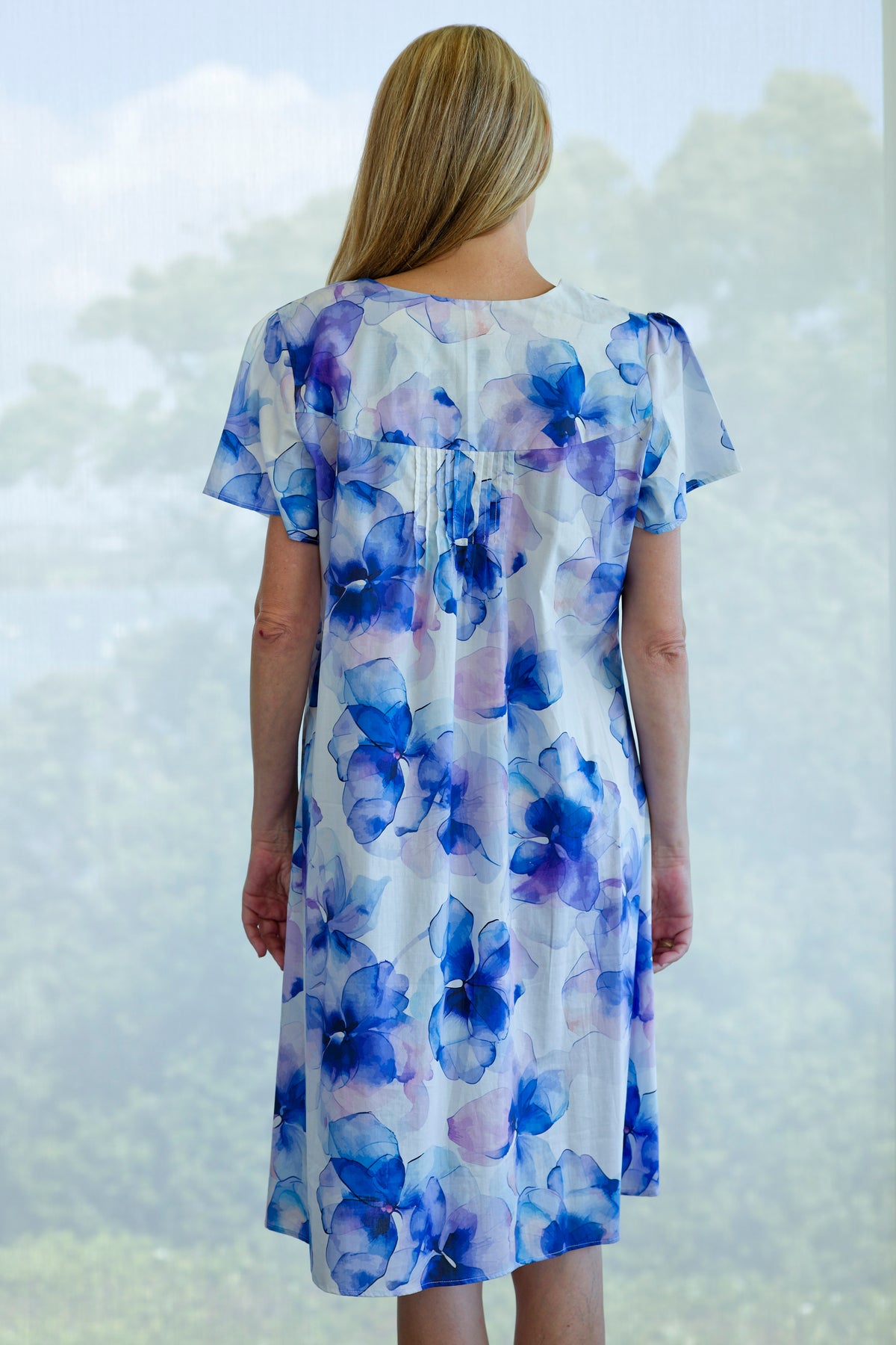 women waring a short sleeve cotton nightie with a blue flower print
