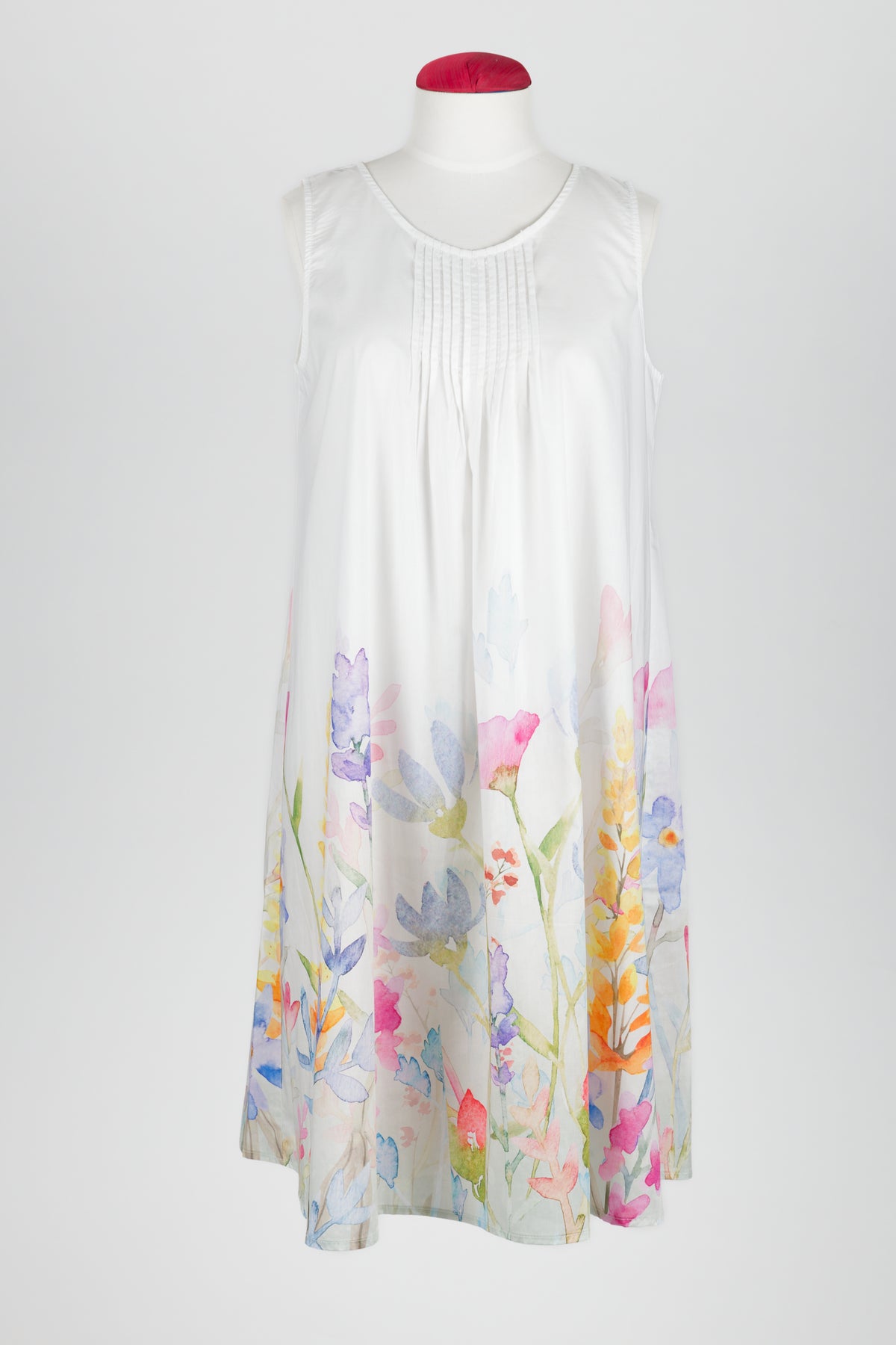 A sleeveless white night dress with a delicate pastel floral print concentrated along the lower hem, displayed on a mannequin against a light gray background.