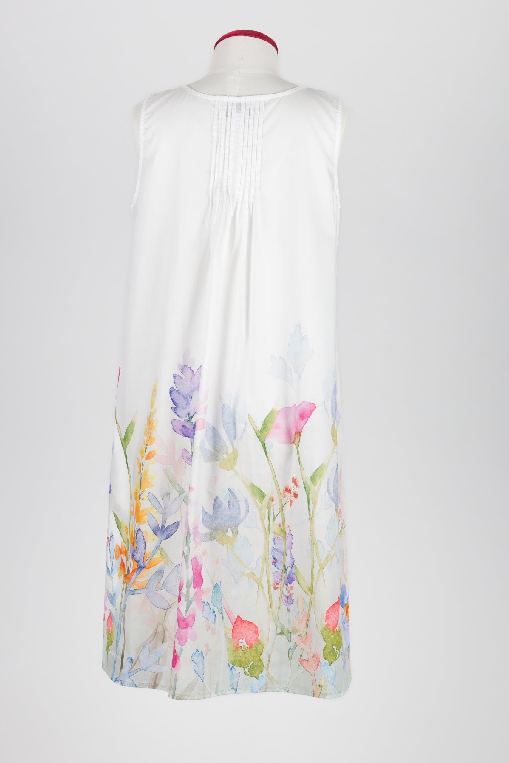 A sleeveless white nightdress displayed on a mannequin against a light gray background, featuring a watercolor floral print concentrated along the lower hem.