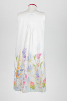 A sleeveless white nightdress displayed on a mannequin against a light gray background, featuring a watercolor floral print concentrated along the lower hem.
